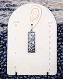 Decorative earring on a measurement card with wheat in the background