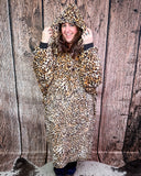Person wearing a leopard print blanket hoodie against a wooden background
