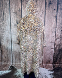 Person wearing a leopard print blanket hoodie against a wooden background