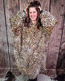 Person wearing a leopard print blanket hoodie against a wooden background