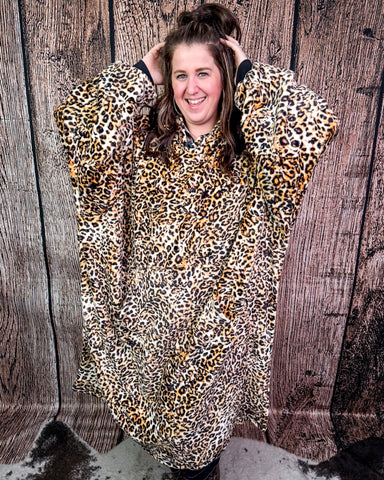 Person wearing a leopard print blanket hoodie against a wooden background