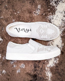 White slip-on sneakers with on a textured brown surface