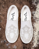 White slip-on shoes with on a textured brown and white surface