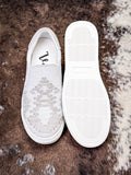 White slip-on sneakers on a textured brown surface