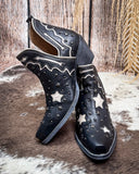 Black cowboy boots with star patterns on a rustic wooden background