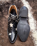 Black leather shoe with star patterns on a textured surface, displaying the brand 'MYRA'.