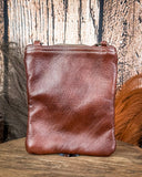 Brown leather crossbody bag on a wooden surface with a rustic background