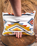 Handle slot on a colorful patterned travel blanket on a wooden stool with a natural background