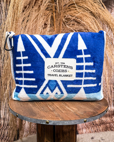 Blue and white travel blanket with Carstens Cozies branding on a wooden stool.