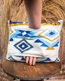 Handle slot on a patterned blanket with geometric design on a wooden stool.