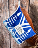 Blue and white patterned travel blanket with brand label on a wooden surface