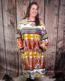 Person wearing a patterned blanket hoodie standing against a wooden background