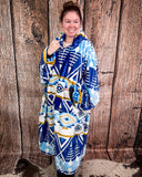 Person wearing a blue and white patterned hooded blanket against a wooden background