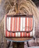 Picnic blanket with red and beige pattern on a wooden stand against a rustic background