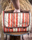 Picnic blanket with red and beige pattern on a wooden stand against a rustic background