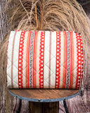 Picnic blanket with red and beige pattern on a wooden stand against a rustic background