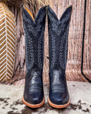  Tall Western boots on Cowhide rug with Boot stich design  brown board in background 