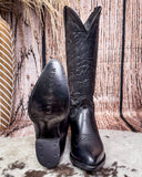 Black Leather boots on cowhide rug, one boot showing off it's rubber heel cap 