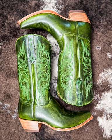 Green cowboy boots with intricate designs on a textured surface