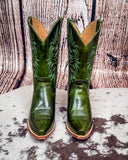 Green cowboy boots with intricate designs on a wooden surface