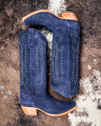 Pair of blue cowboy boots with white stitching on a textured surface