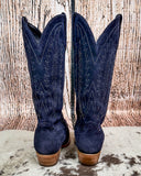 Pair of navy blue cowboy boots with white stitching on a textured surface.