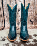 Pair of teal cowboy boots with brown soles on a rustic wooden background