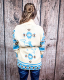 Person wearing a patterned cardigan against a wooden background