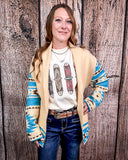 Woman wearing a patterned cardigan over a graphic t-shirt with a wooden background