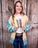 Woman wearing a patterned cardigan over a graphic t-shirt against a wooden background