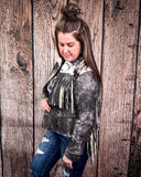 Woman wearing a fringed jacket against a wooden background