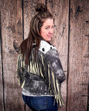 Woman wearing a fringed leather jacket against a wooden background