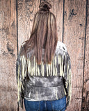 Person wearing a fringed leather jacket against a wooden background