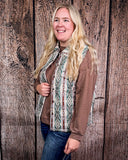 Woman wearing a patterned vest over a brown shirt against a wooden background
