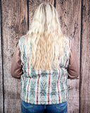 Person wearing a patterned vest with a wooden background