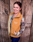 Woman wearing a beige vest with a wooden background