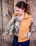 Woman wearing a beige quilted vest against a wooden background