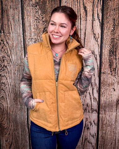 Woman wearing a beige vest against a wooden background