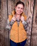 Woman wearing a beige puffer vest against a wooden background