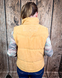 Person wearing a beige puffer vest against a wooden background