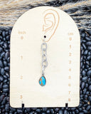 Earring on a measurement card with black beans in the background