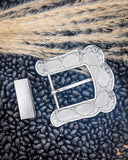 Back side of a belt buckle displayed on black beans.