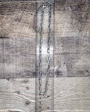 Long silver chain on a wooden surface with a ruler for scale