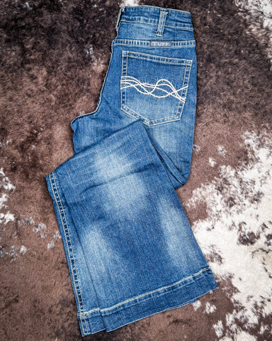 Folded blue jeans on a textured brown surface