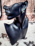 Earring worn on black display mannequin.