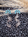 Filigree spiral earrings with turquoise flowers on rustic background.