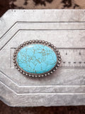 Oversized turquoise Western belt buckle with silver detailing shown on ruler for size reference