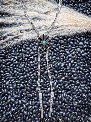 Southwestern bolo tie with silver beads and turquoise flower center styled flat lay