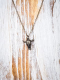 Gold toned steer head necklace on a wooden background