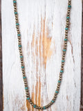 Gold and turquoise toned beaded necklace on a wooden background